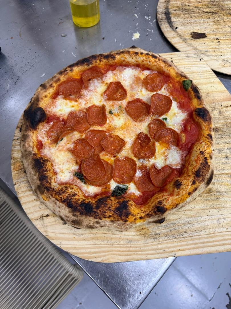 Pizza pepperoni artesanal en pala de madera