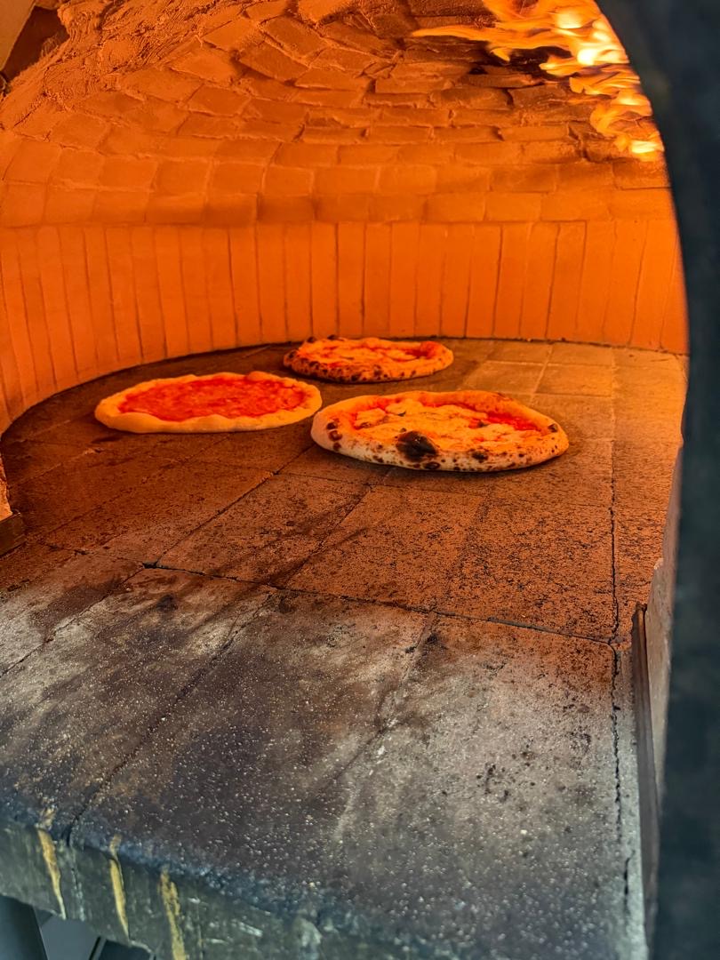 Pizzas horneándose en el horno de leña