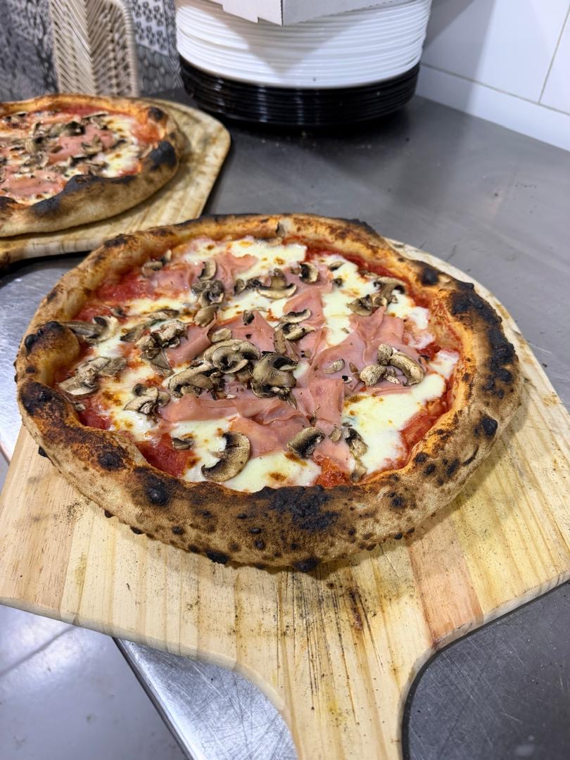 Pizza prosciutto e funghi recién salida del horno